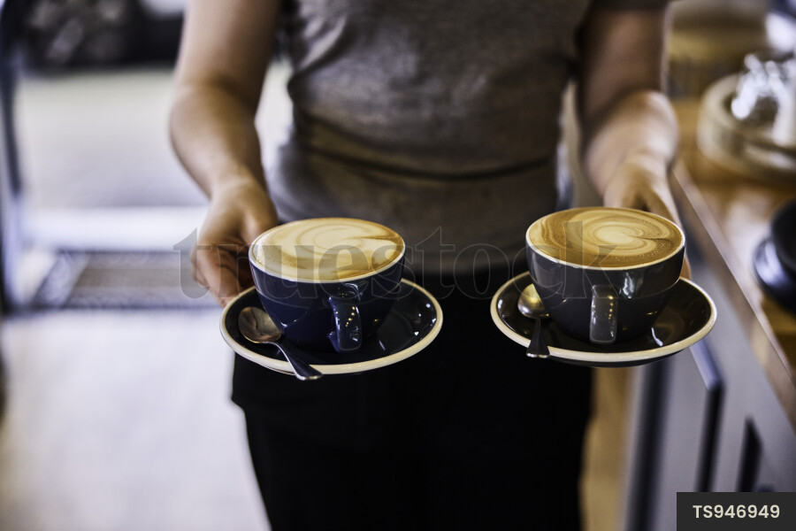 Close up of waitress carrying coffee in cafe