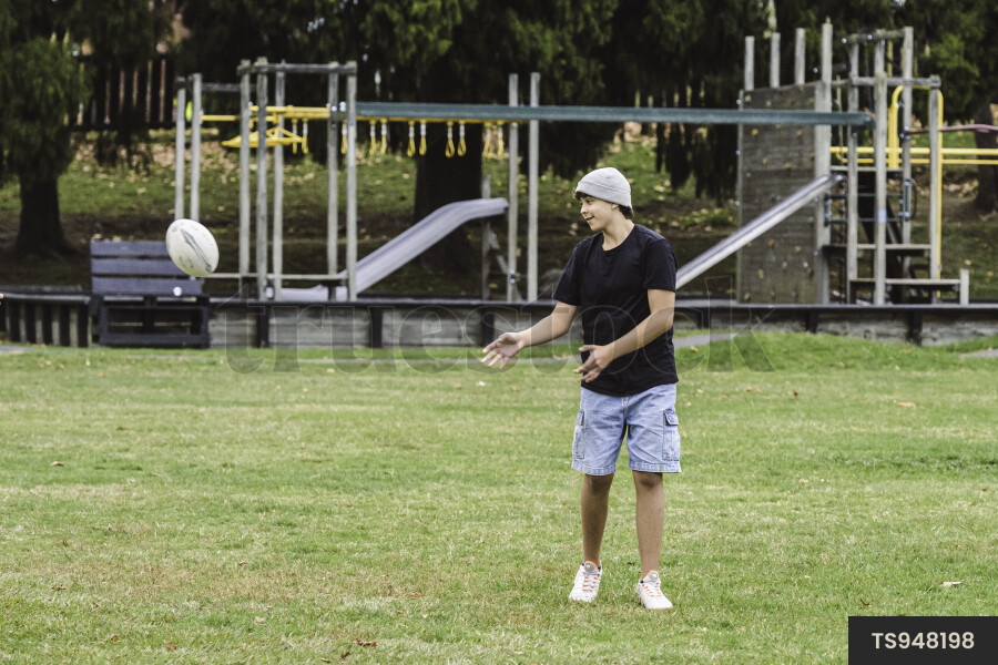 Teenage boy playing rugby in park