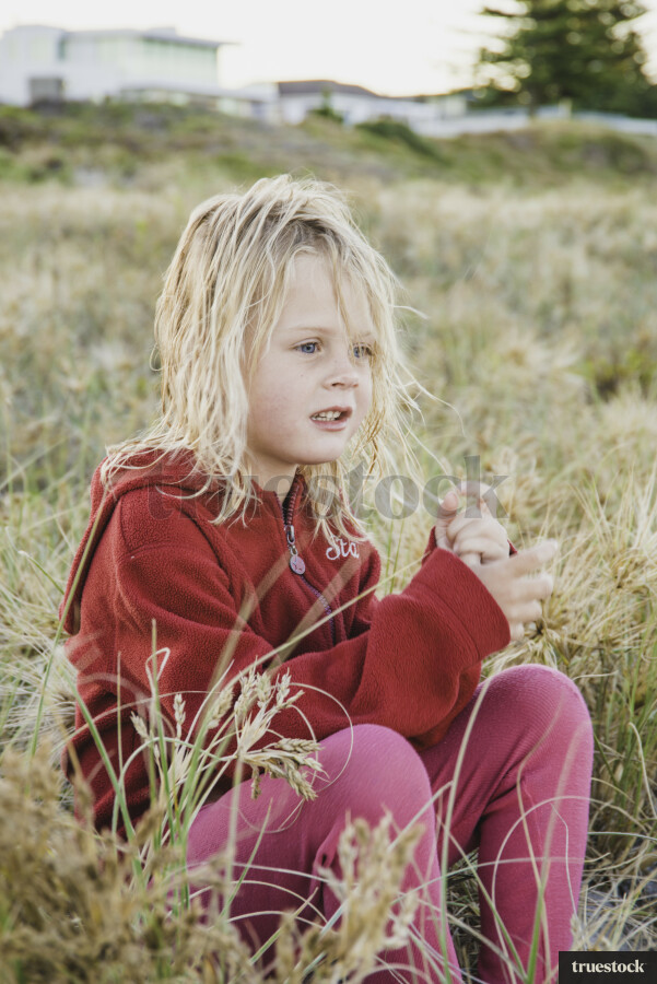 Young Girl sitting in Grass at Beach
