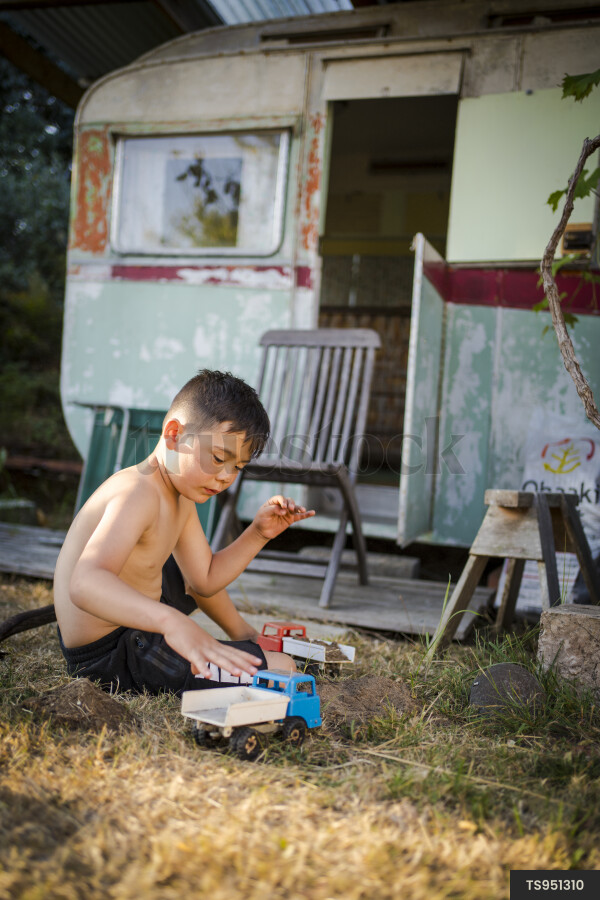 Boy playing with toy truck by caravan