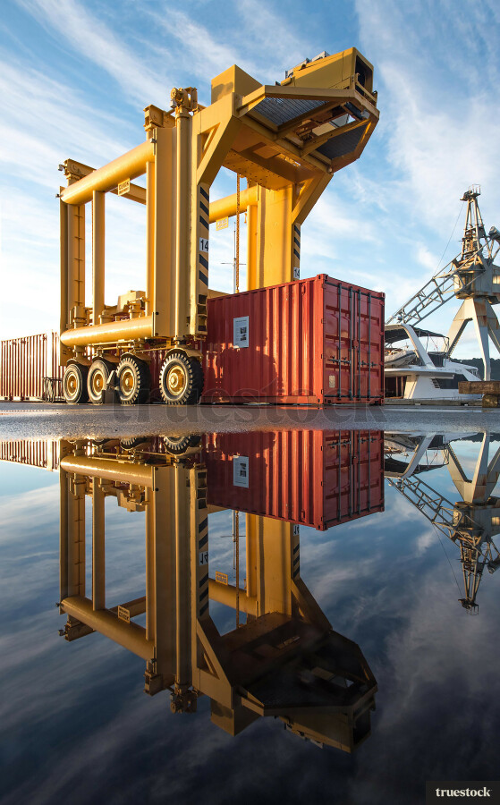 Reflection of container and crane in the water on the concrete