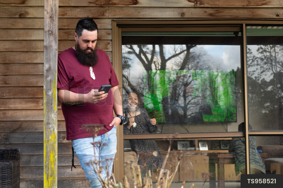 Man Using Phone on Porch