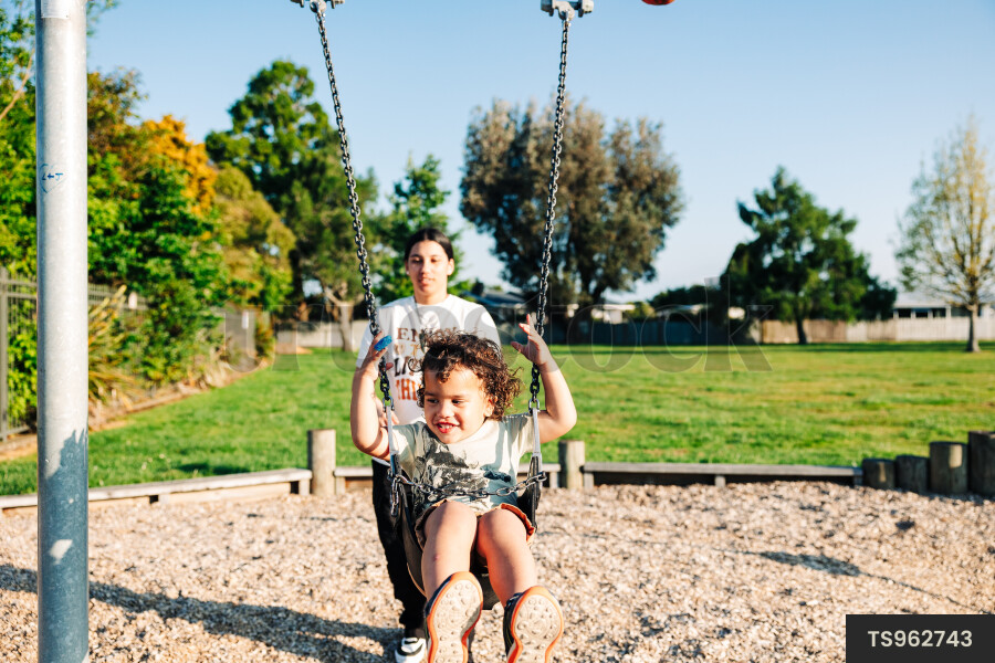 Girl and her brother playing on swing at park