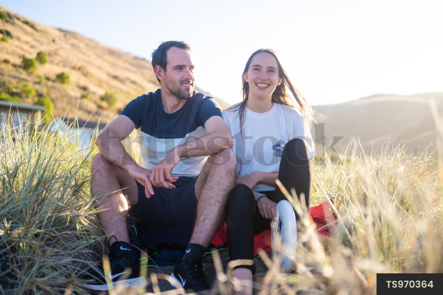 Couple sitting in grass at sunset