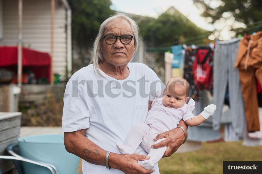 Grandfather Holding Granddaughter in Backyard
