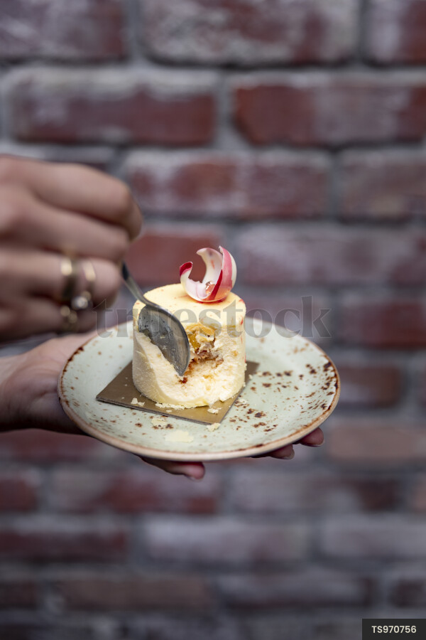 Woman with spoon scoops from dessert on plate