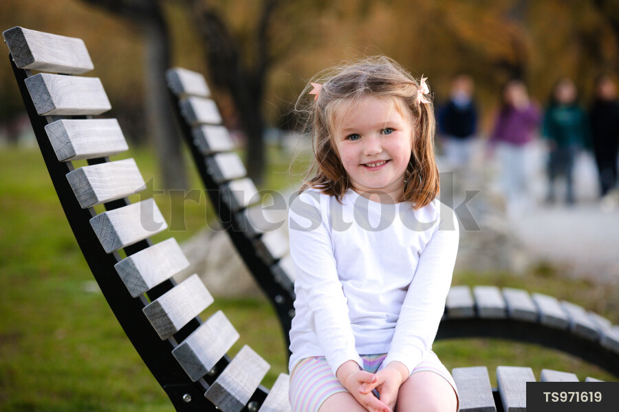Portrait of girl sitting on bench in park