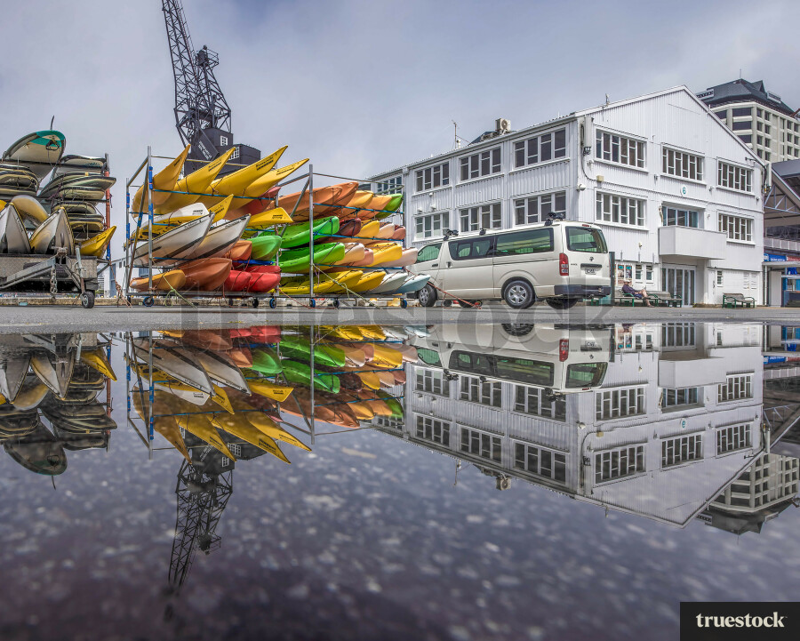 Reflection of kayaks and buildings in the water on the concrete