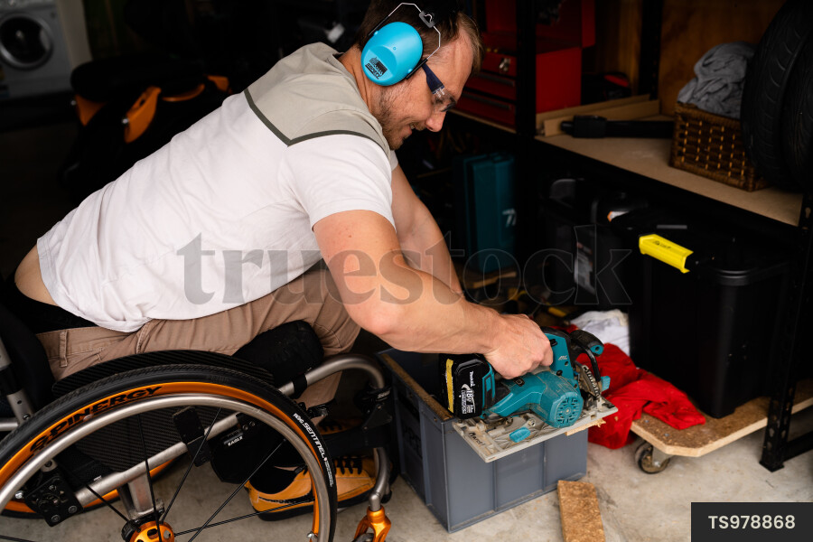 Man in wheelchair doing DIY in garage