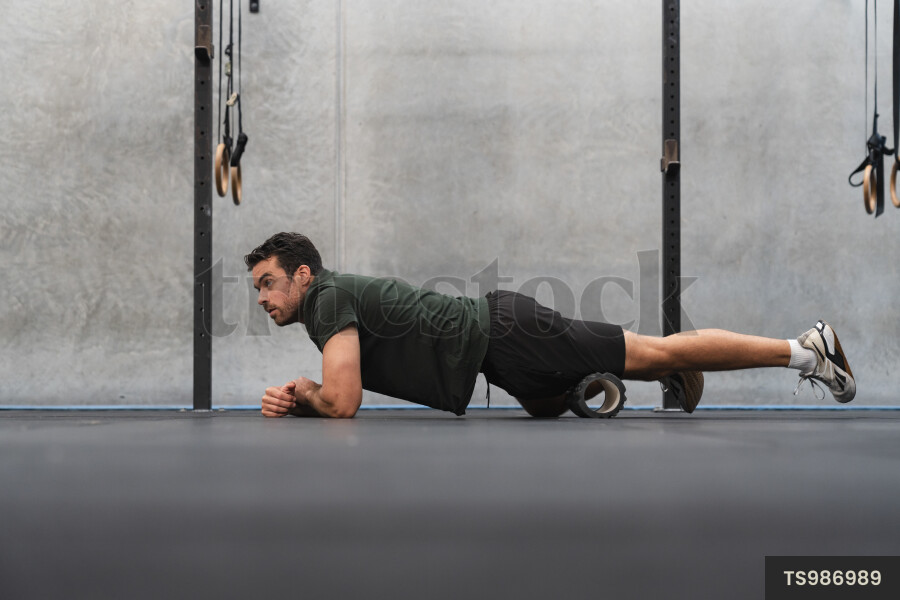 Young man warming up using exercise equipment in gym