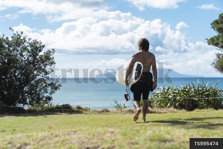 Surfer with surfboard in paddock by sea
